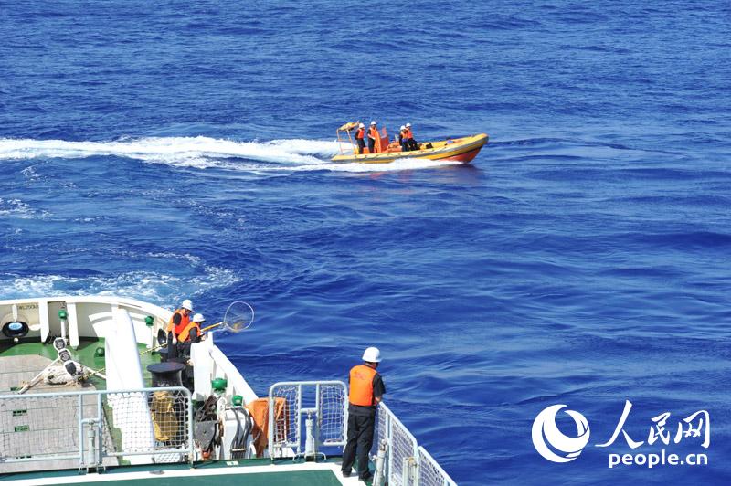 4月1日，“海巡01”在澳方今日公布的重點搜尋片區進行疑似物打撈、排除。圖為海巡01船載高速救生艇協同打撈組工作人員在后甲板等待打撈疑似漂浮物。張馳攝