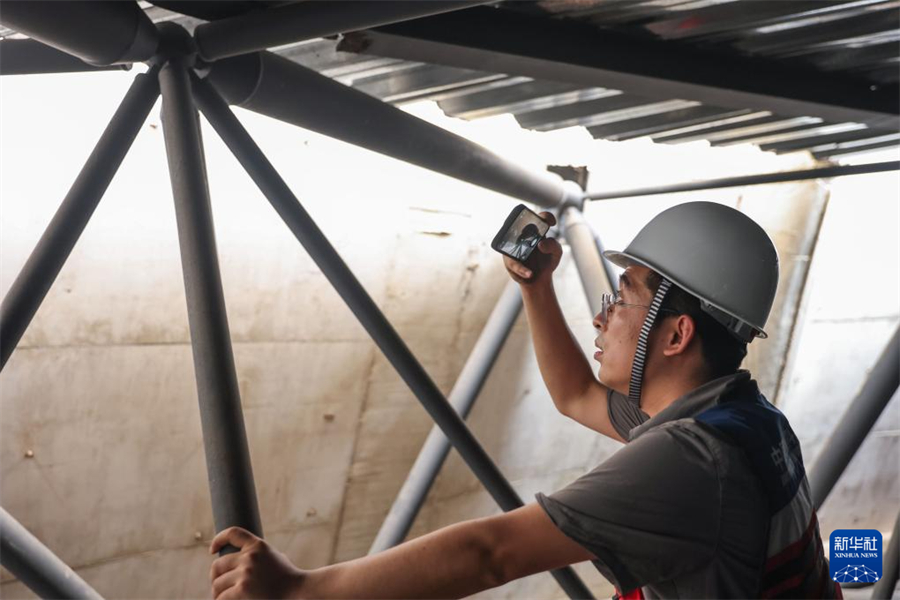 1月1日，在瓦努阿圖維拉港，中國地震局工程力學研究所副研究員柏文在一棟建筑的結構頂部網架位置記錄受損情況。新華社記者 龍雷 攝